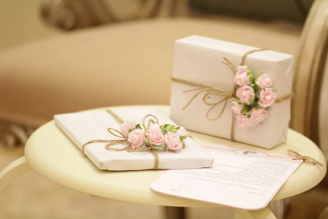 A elegantly styled reception table with rows of personalized honey jar favors, seed packet envelopes, and monogrammed gift boxes arranged beside floral centerpieces